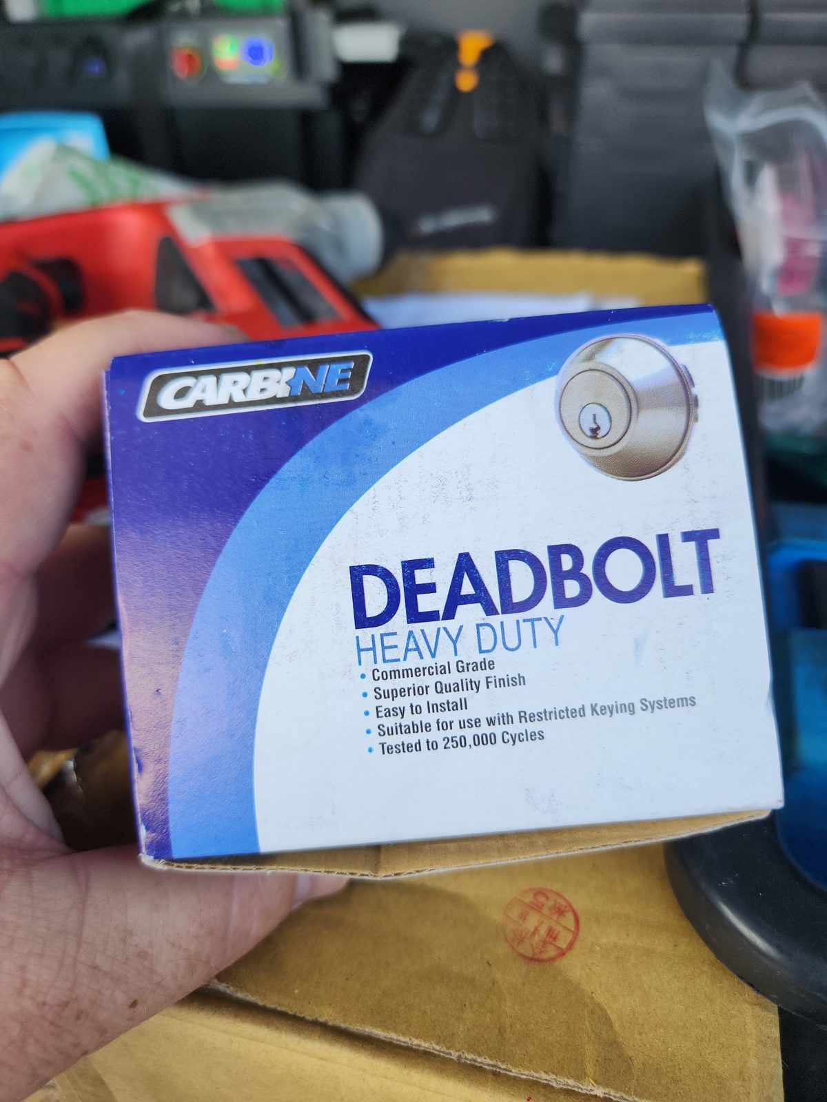 A heavy-duty commercial grade deadbolt, boxed, in the back of the work van